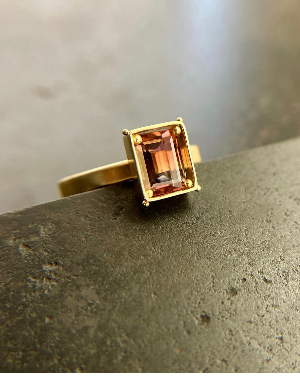 A rectangular pink ombre tourmaline stone ring in gold setting.
