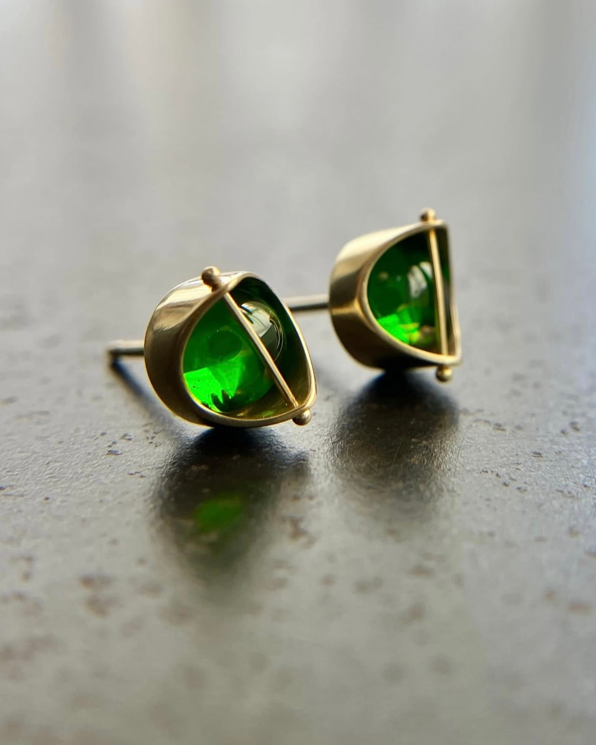 Bright green chrome diopside cabuchon stud earrings in gold settings.
