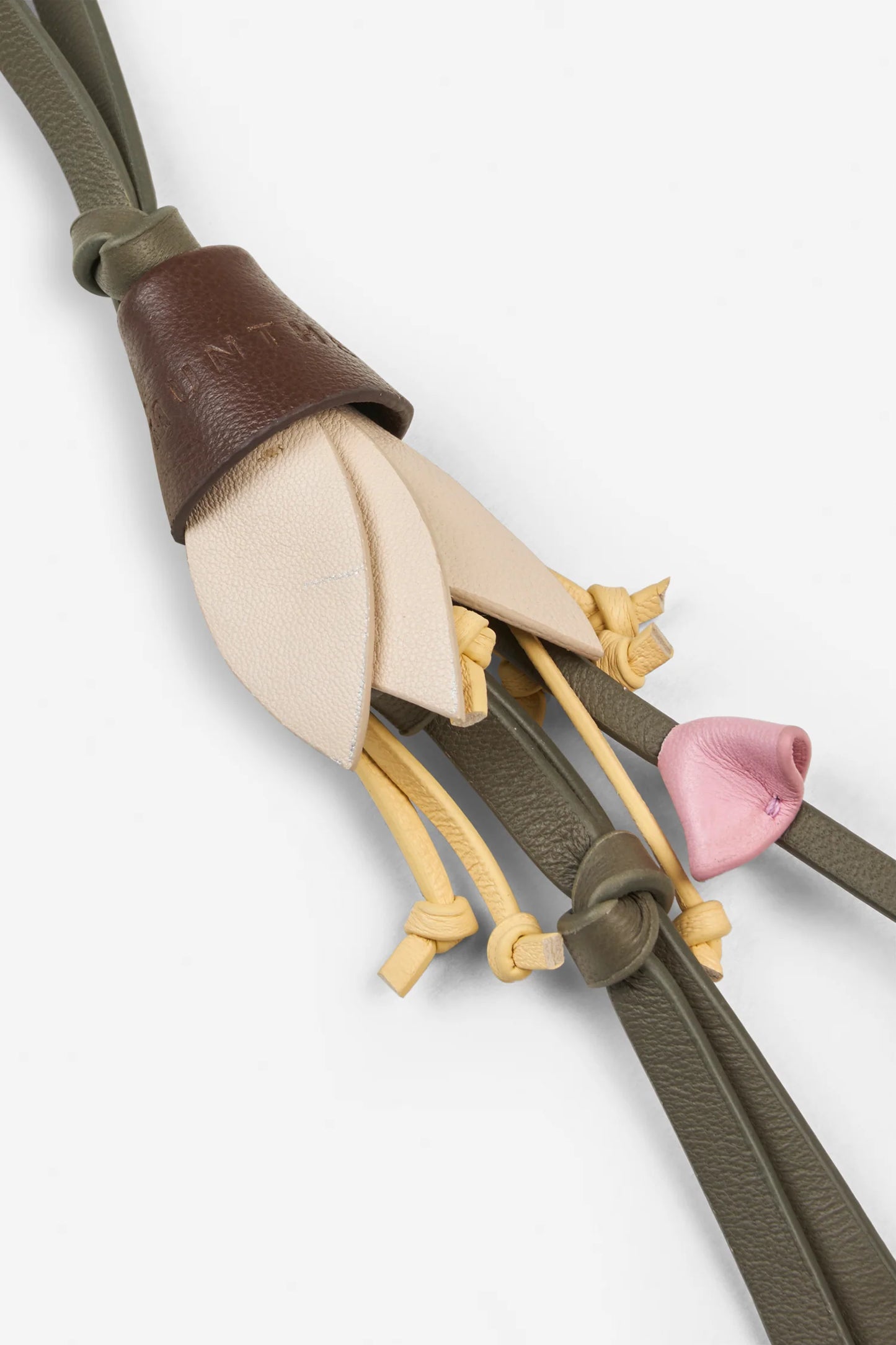 Close-up of a decorative leather strap with tassels on a white background