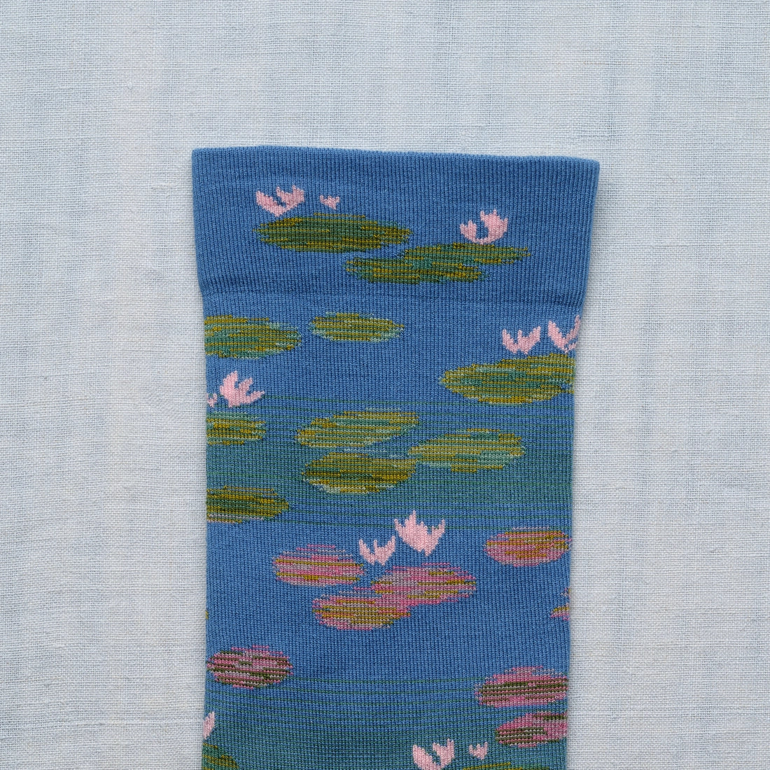 A closeup of a blue sock with a monet water lily design.