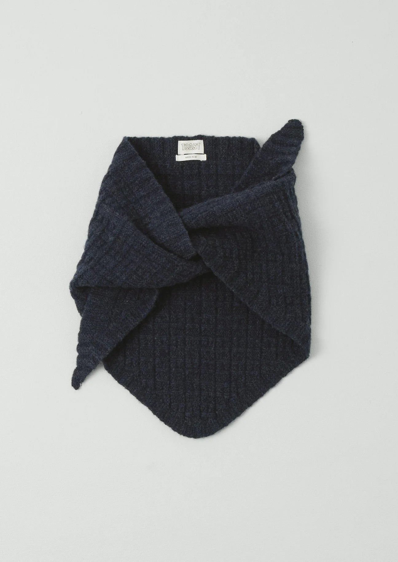 Dark blue knitted scarf on a light gray background
