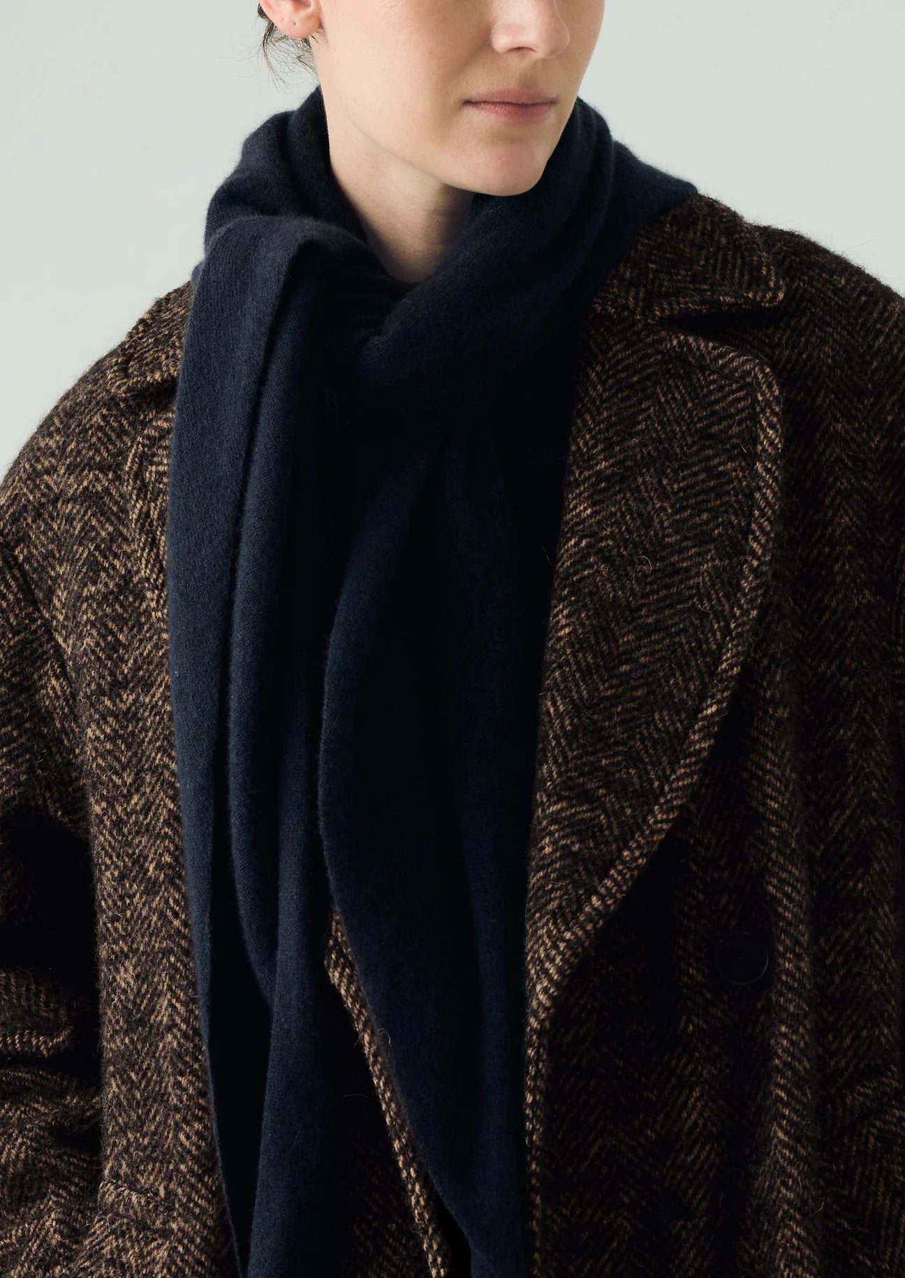 Person wearing a dark coat with a plain background