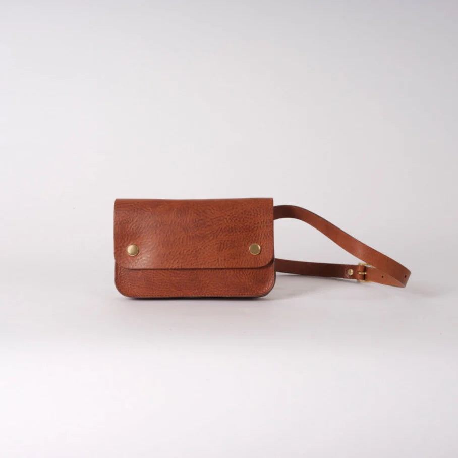 Front view of small crossbody handmade brown leather bag with two brass pop closures.