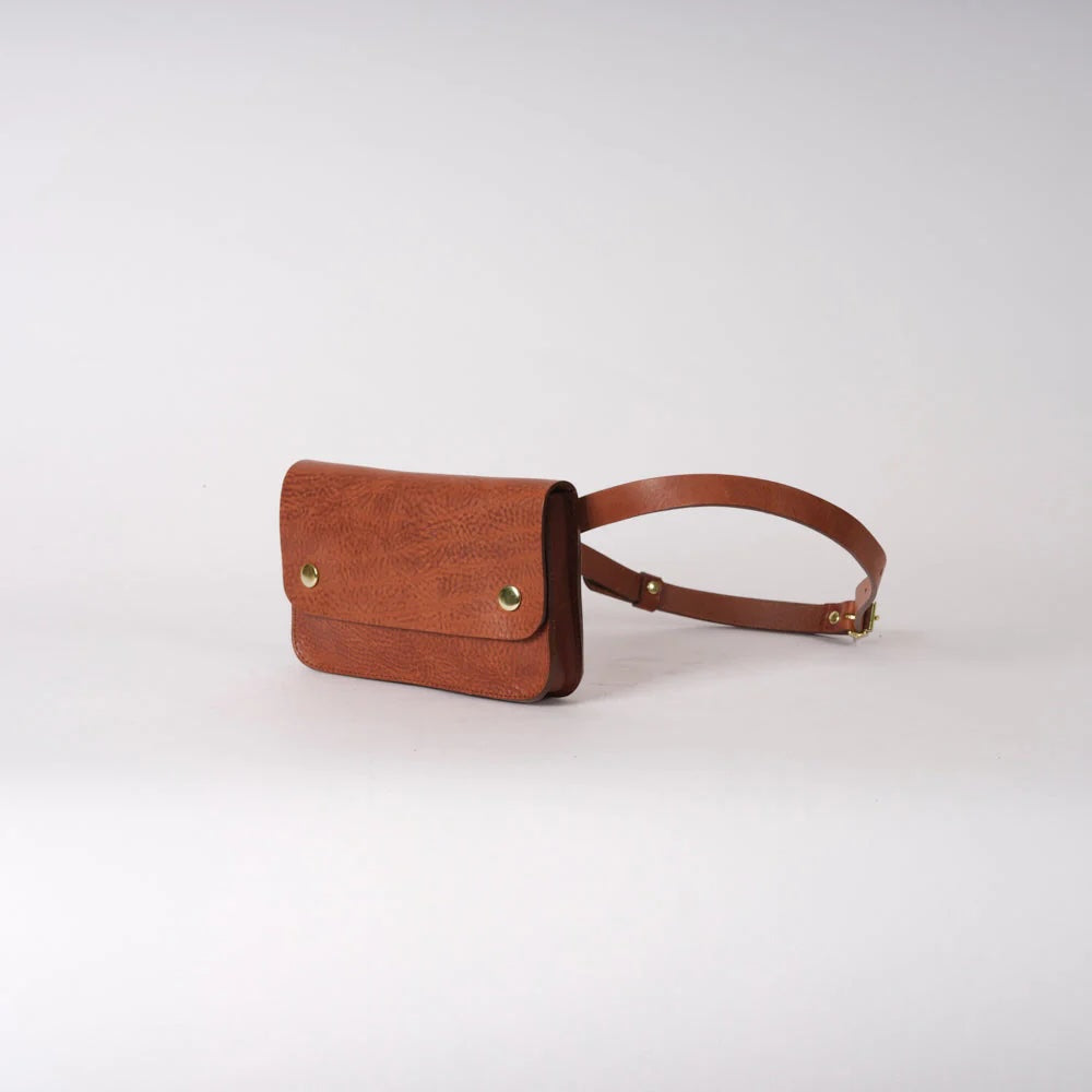 Side view of small crossbody handmade brownl eather bag with two brass pop closures.