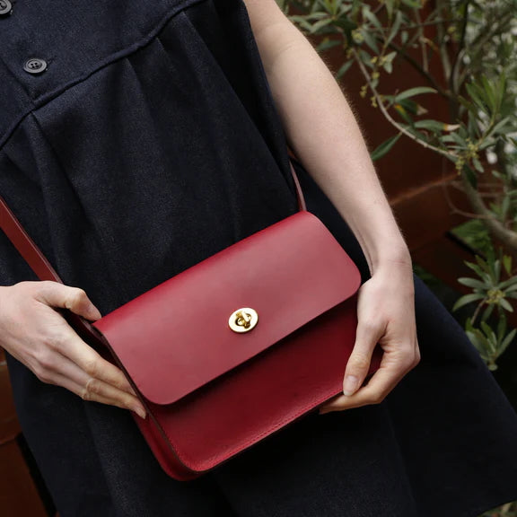 Picture of red leather handbag being held by woman, close up