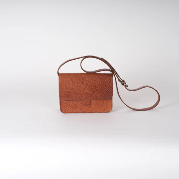 Picture of the front of a brown leather handbag on a plain white background.