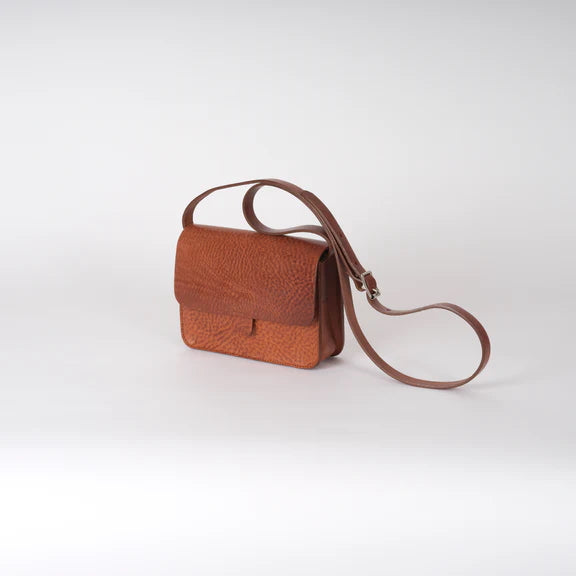 Picture of the front and side of a brown leather handbag on a plain white background.