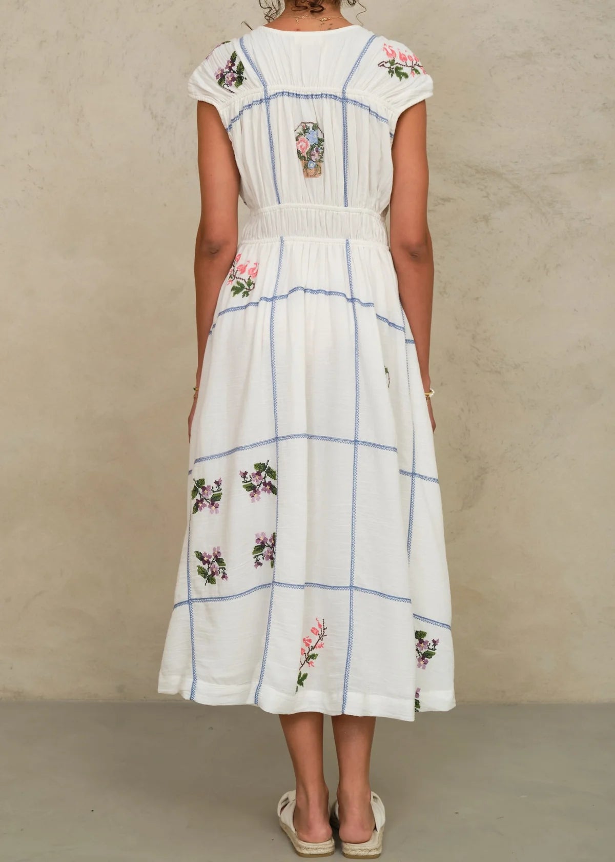 White dress with floral embroidery on a plain background