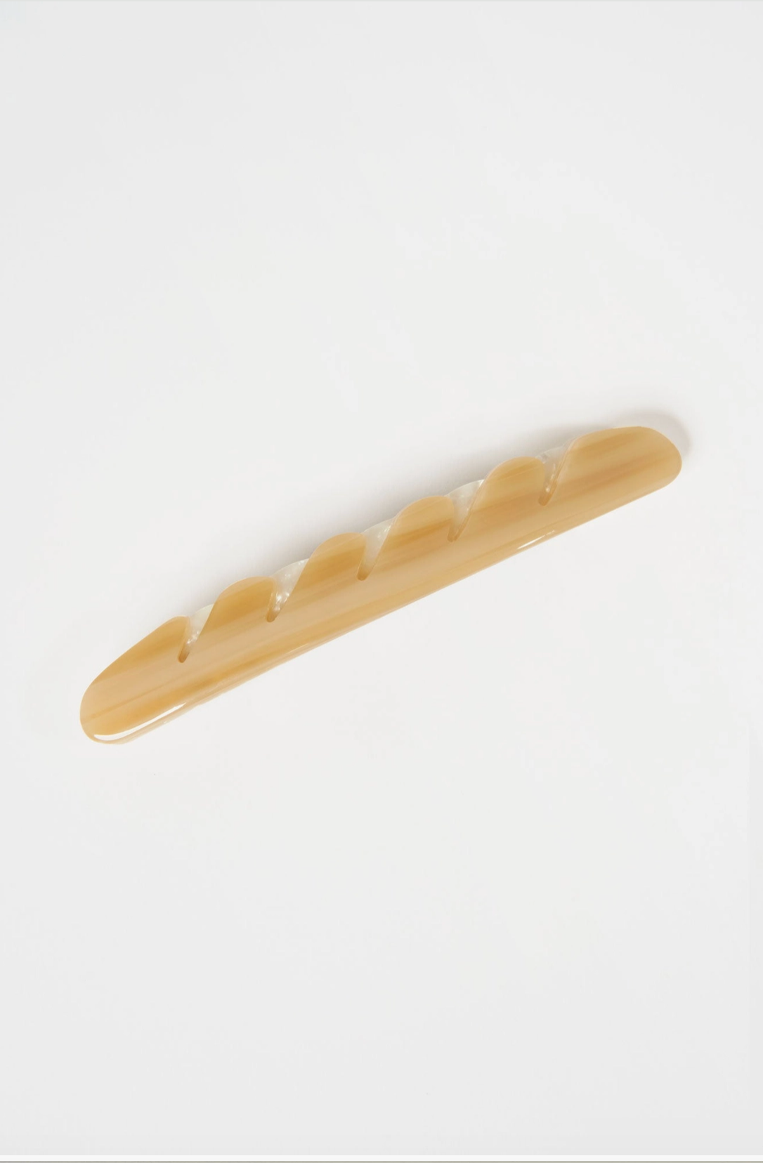 Image of a creme colored hair barrette shaped like a baguette.