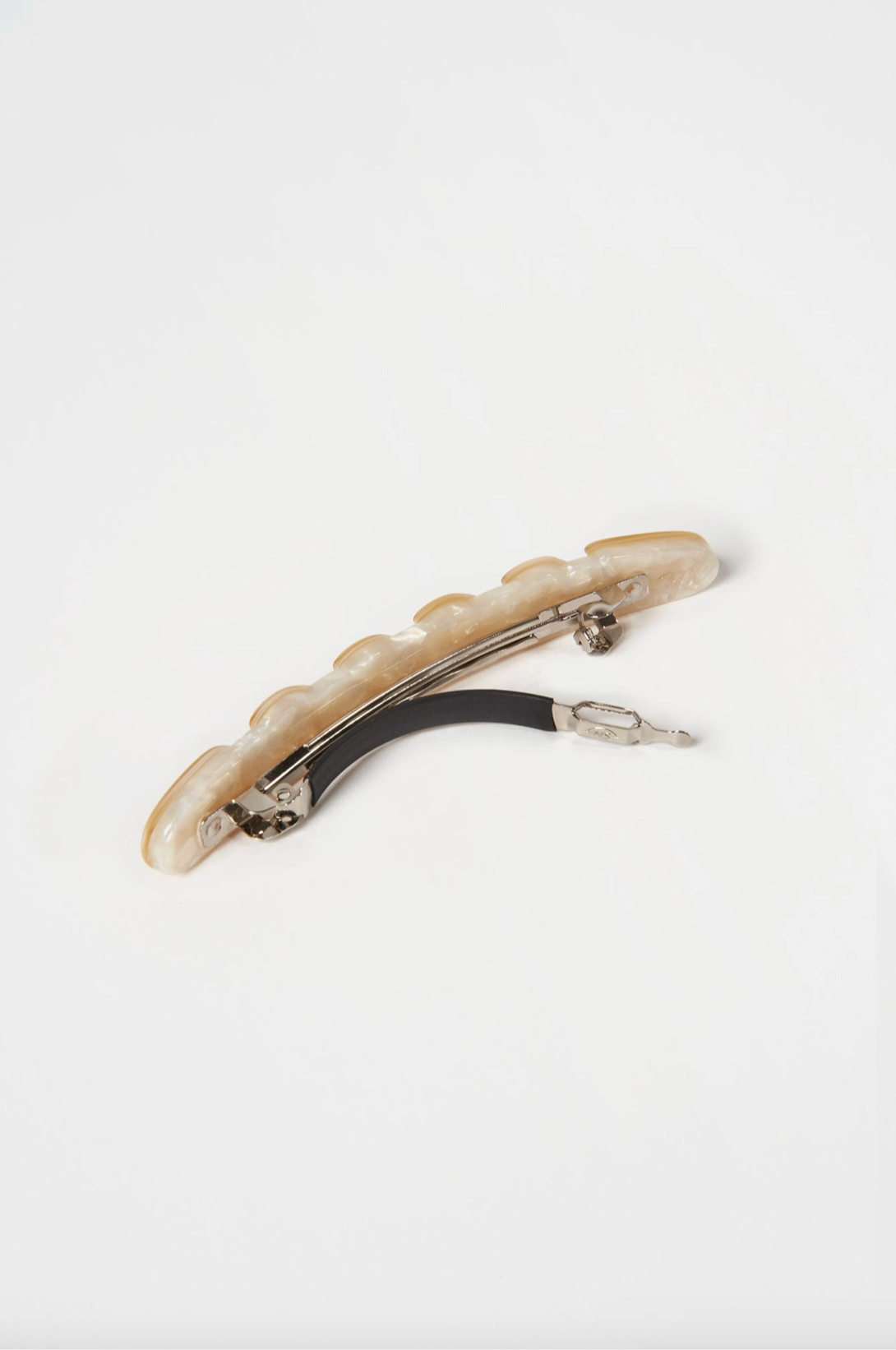 Image of a creme colored hair barrette shaped like a baguette. The clip is laying on it's side to show the clasp mechanism.