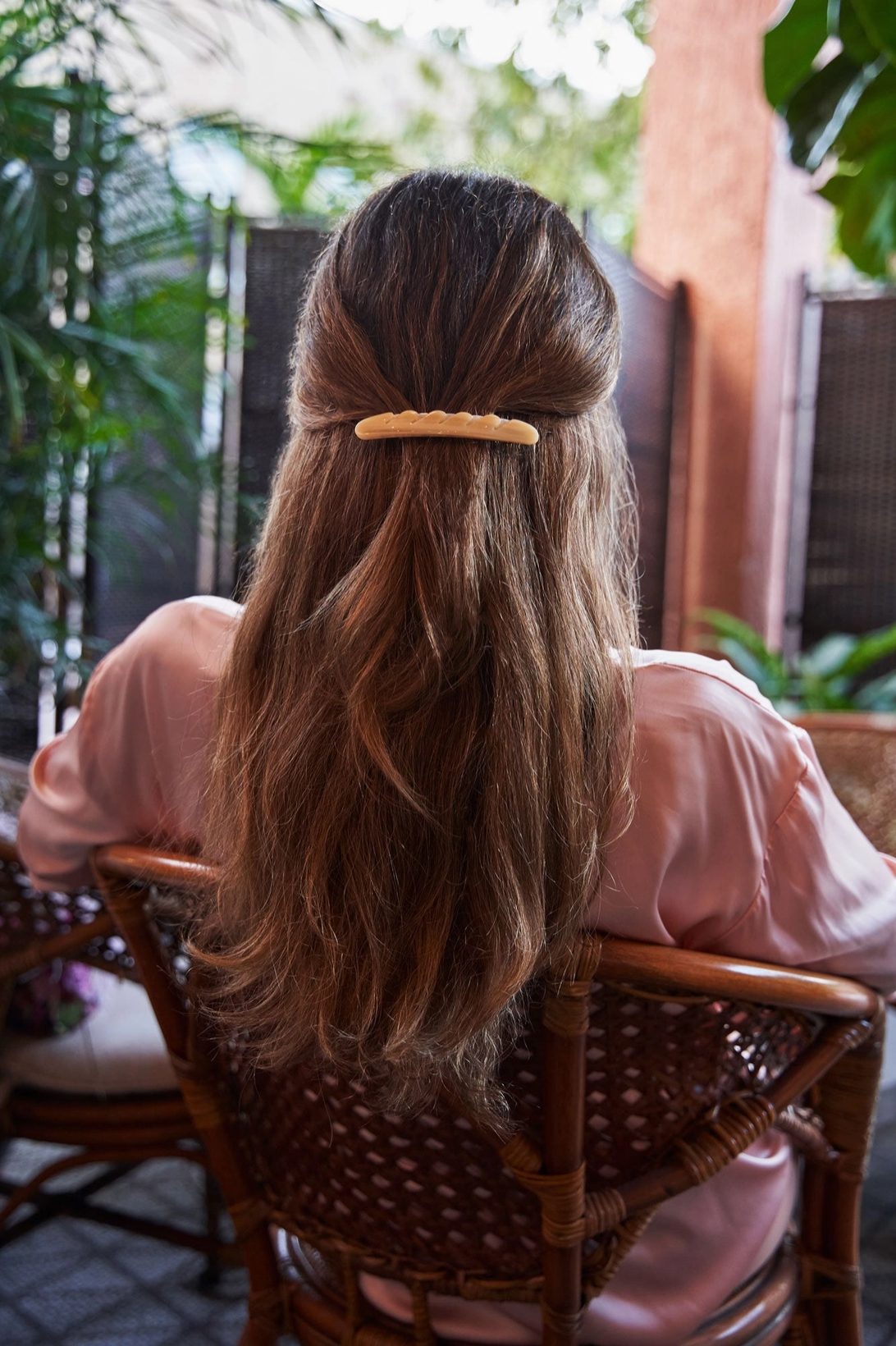 Photo of the back of a woman with long brown hair with a section secured with a baguette shaped barrette.