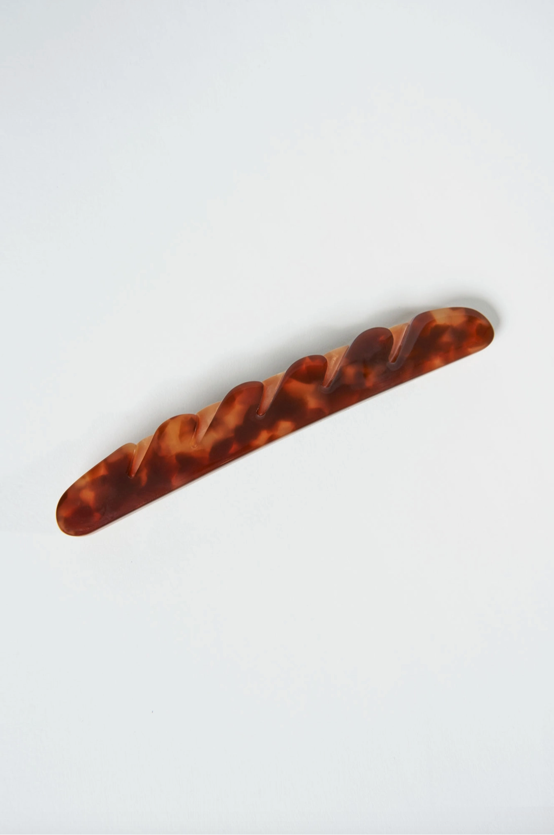 Image of a brown colored hair barrette that is shaped like a baguette.