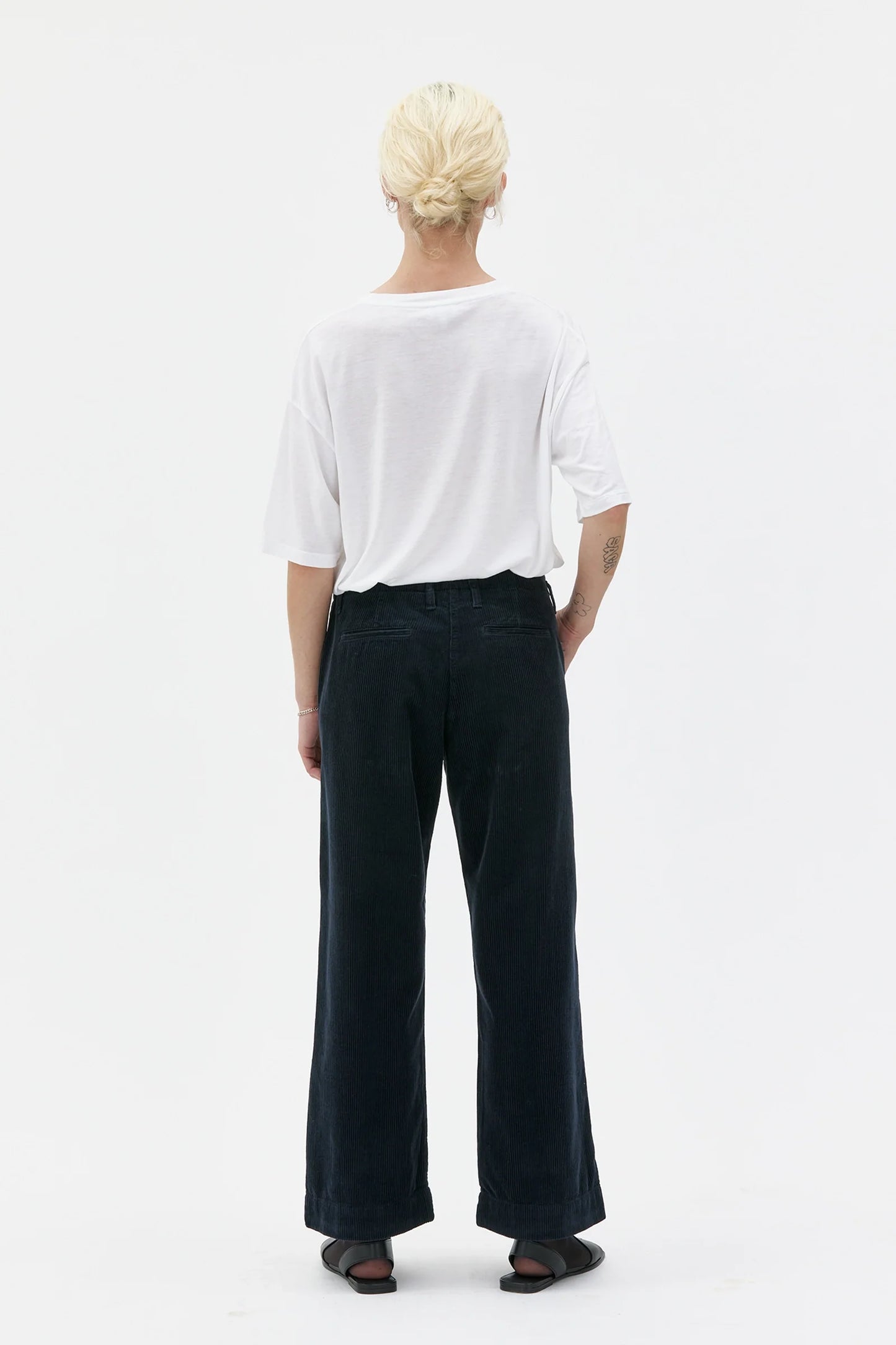 Person wearing a white shirt and black pants on a white background