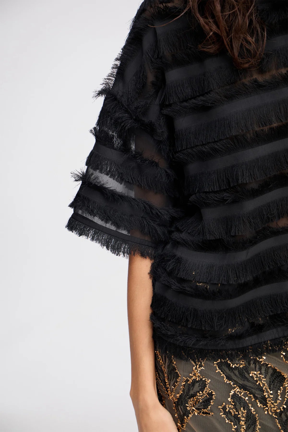 Black fringed garment with a white background