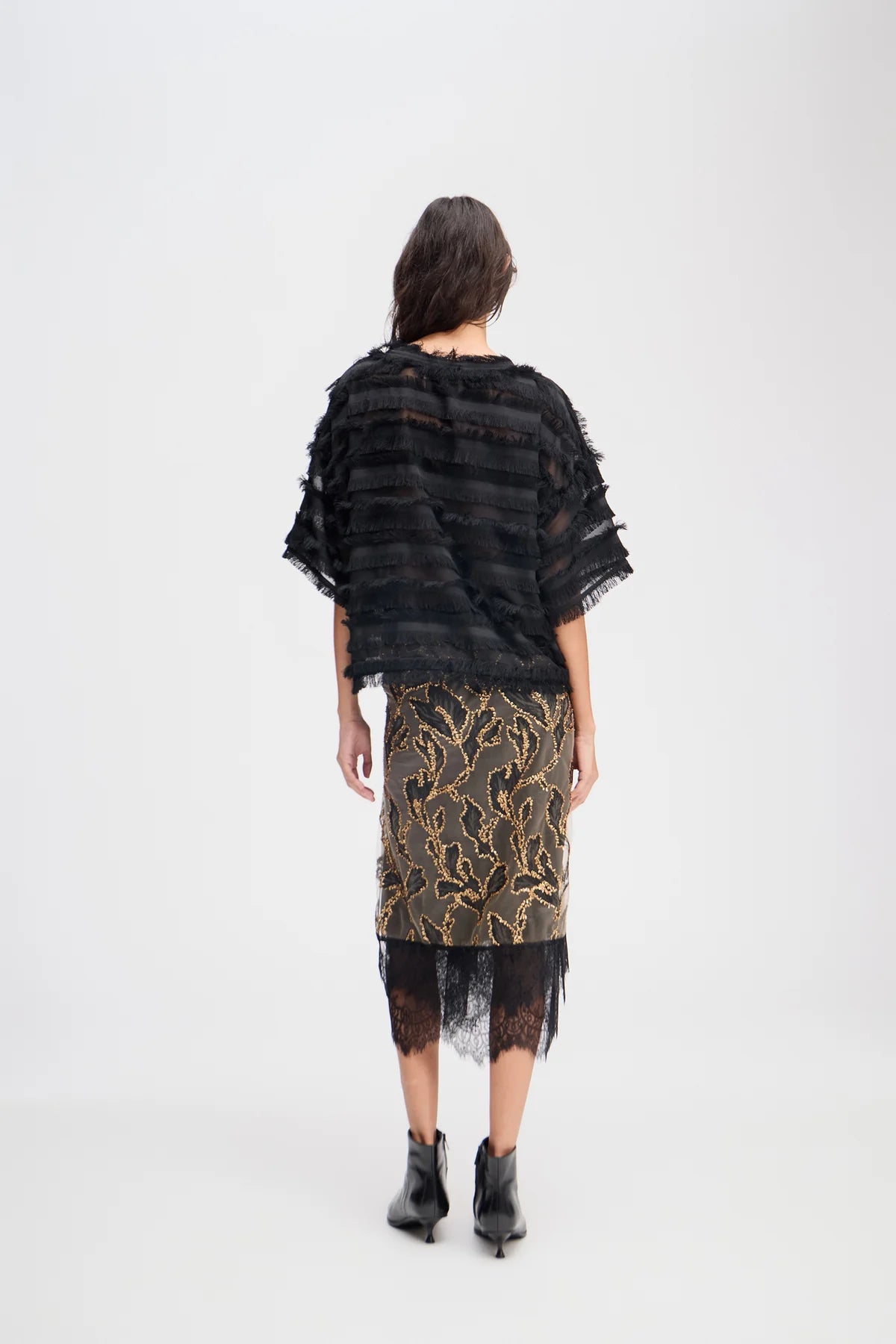 Person wearing a black and gold patterned outfit on a white background