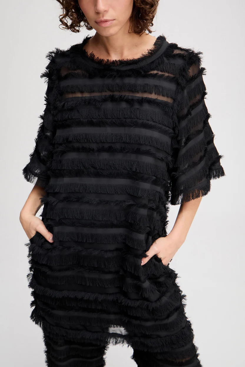 Black ruffled dress worn by a person on a white background