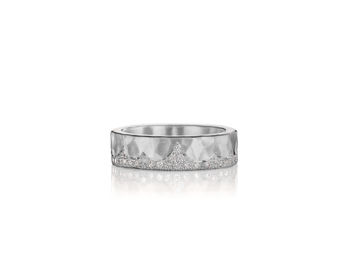 A white gold hammered ring with a mountain range if small diamonds along one side.