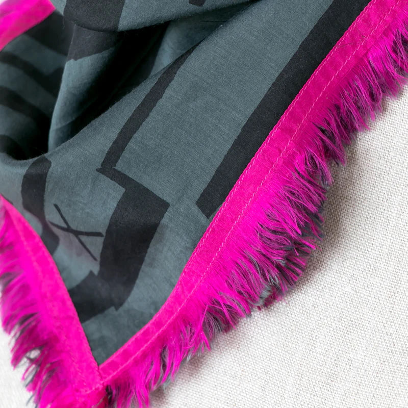 Picture of dark grey and charcoal scarf with pink trim close up on one edge.