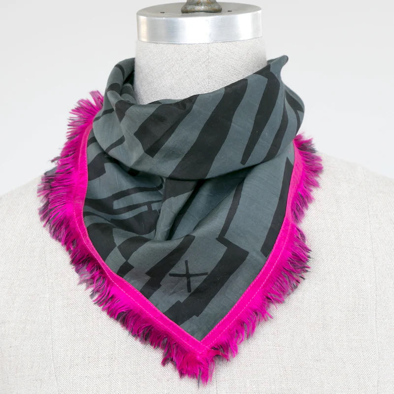 Picture of dark grey and charcoal scarf with pink trim on a mannequin stand.