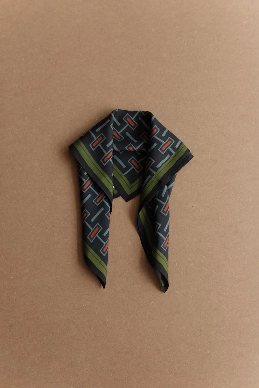 Picture of silk scarf with blue and red geometric pattern. Hanging on invisible hook.