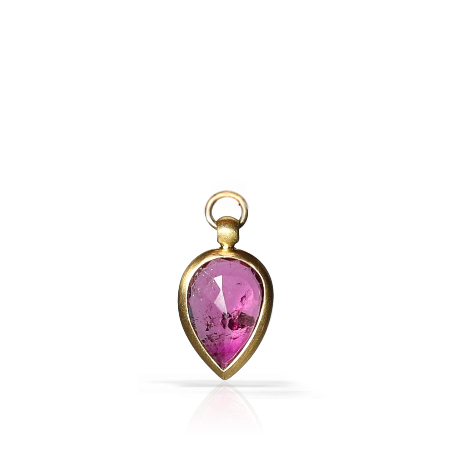 A teardrop-shaped pendant featuring a faceted purple gemstone set in a polished gold-tone metal bezel with a top loop, shown on a clean white background with a soft reflection below.