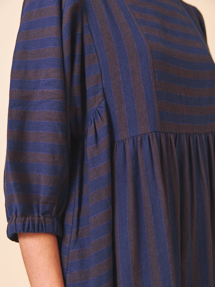 Navy and gray striped dress with long sleeves on a beige background