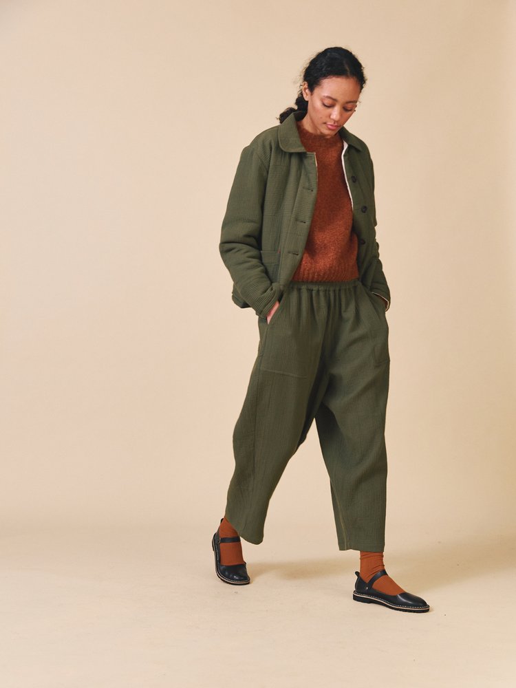 Woman wearing a green outfit with a beige background