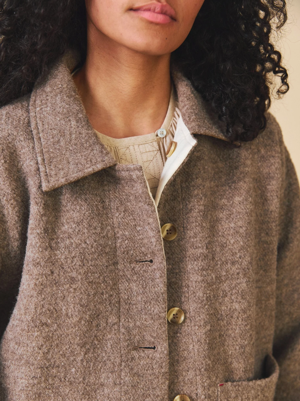 Close-up of a person wearing a brown coat with a neutral background