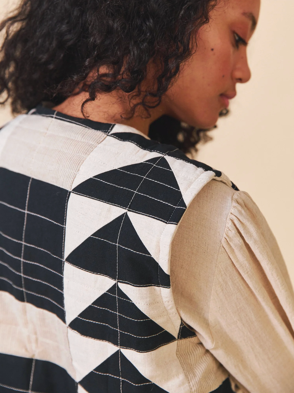 Person wearing a black and white geometric patterned jacket with beige sleeves.