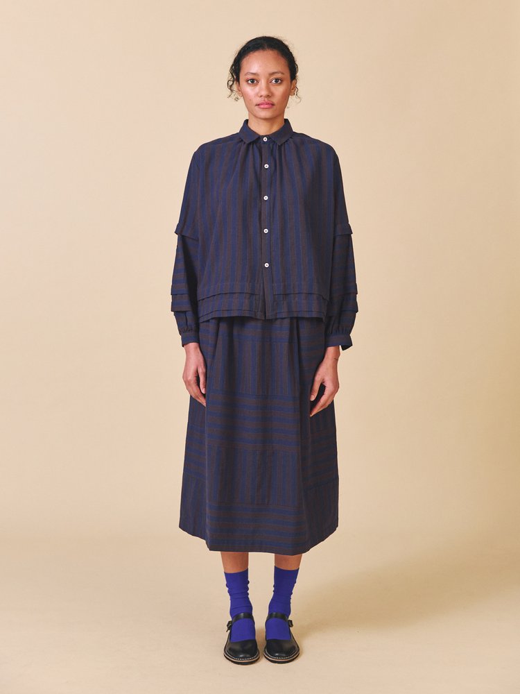 Person wearing a navy striped outfit on a beige background
