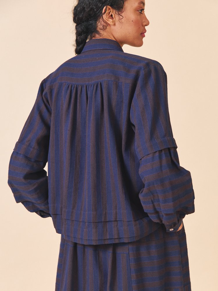 Person wearing a blue striped outfit on a beige background
