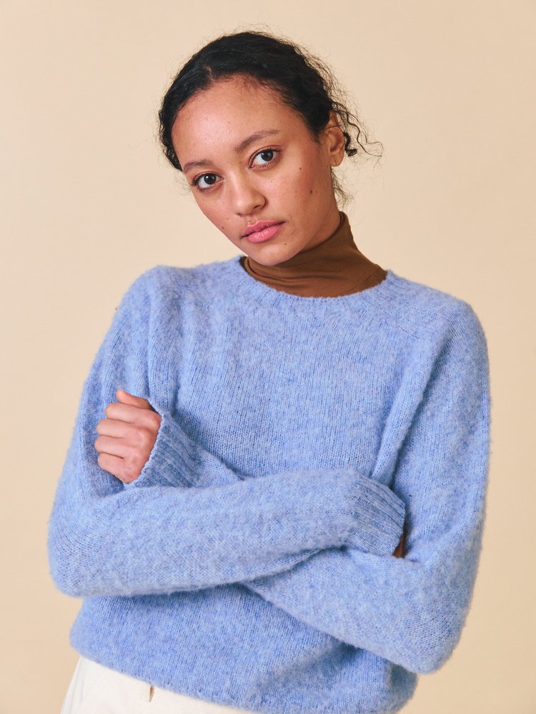 Woman wearing a light blue sweater against a beige background