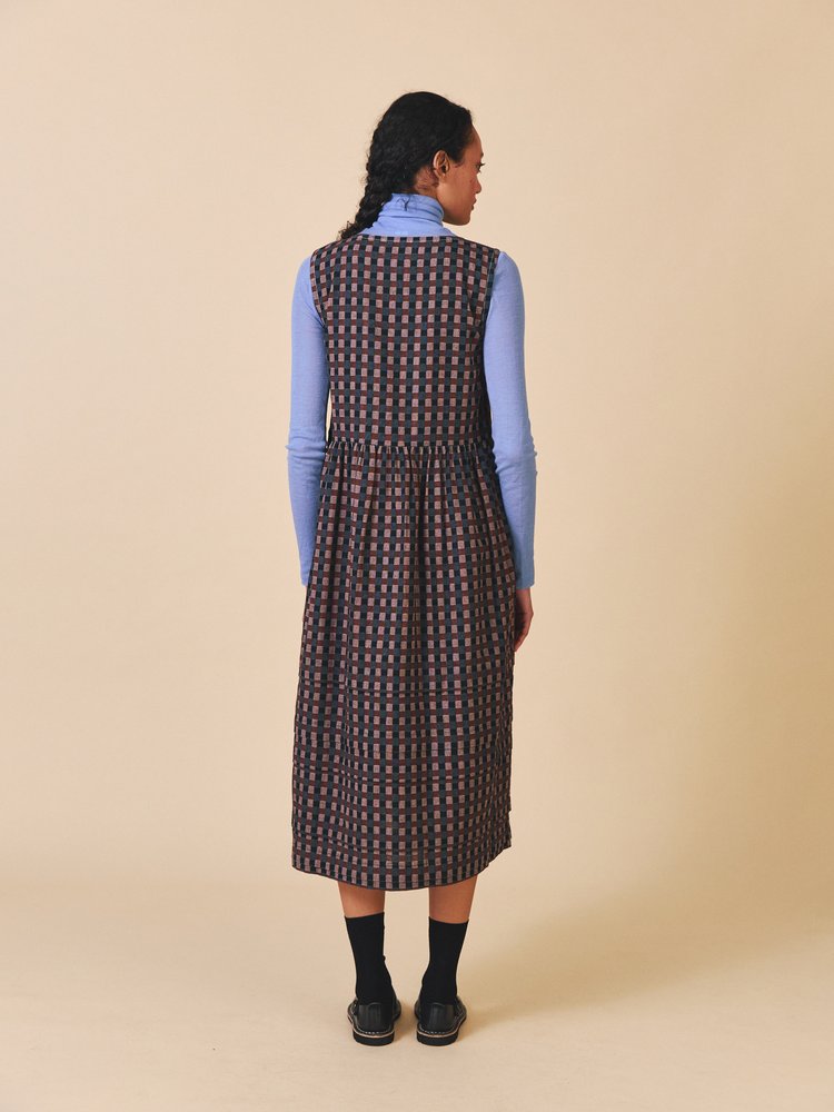 Woman wearing a patterned dress over a blue shirt on a beige background