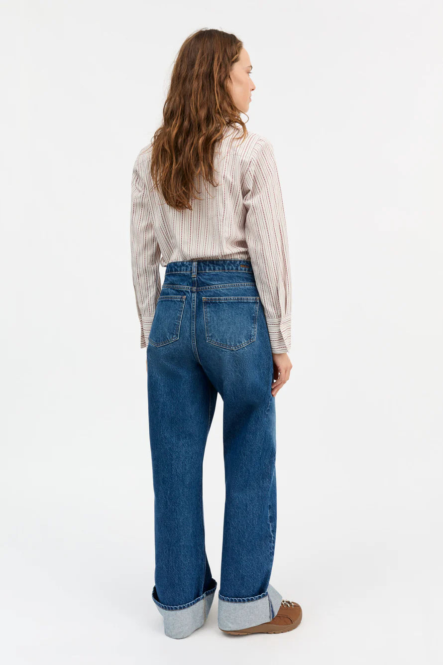 Person wearing blue jeans and a striped shirt on a white background
