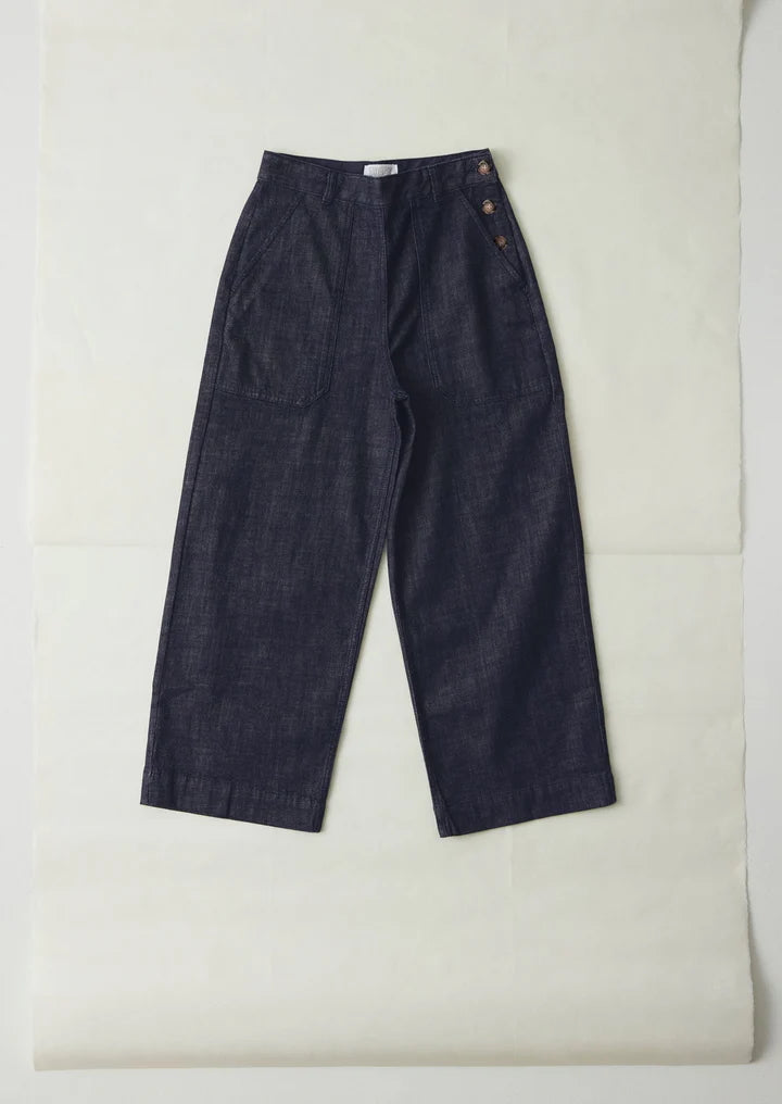 Pair of dark blue denim pants on a light beige background