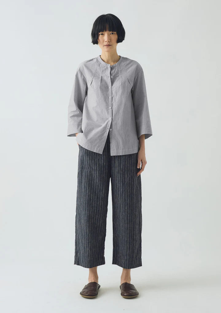 Person wearing a gray shirt and dark striped pants on a white background