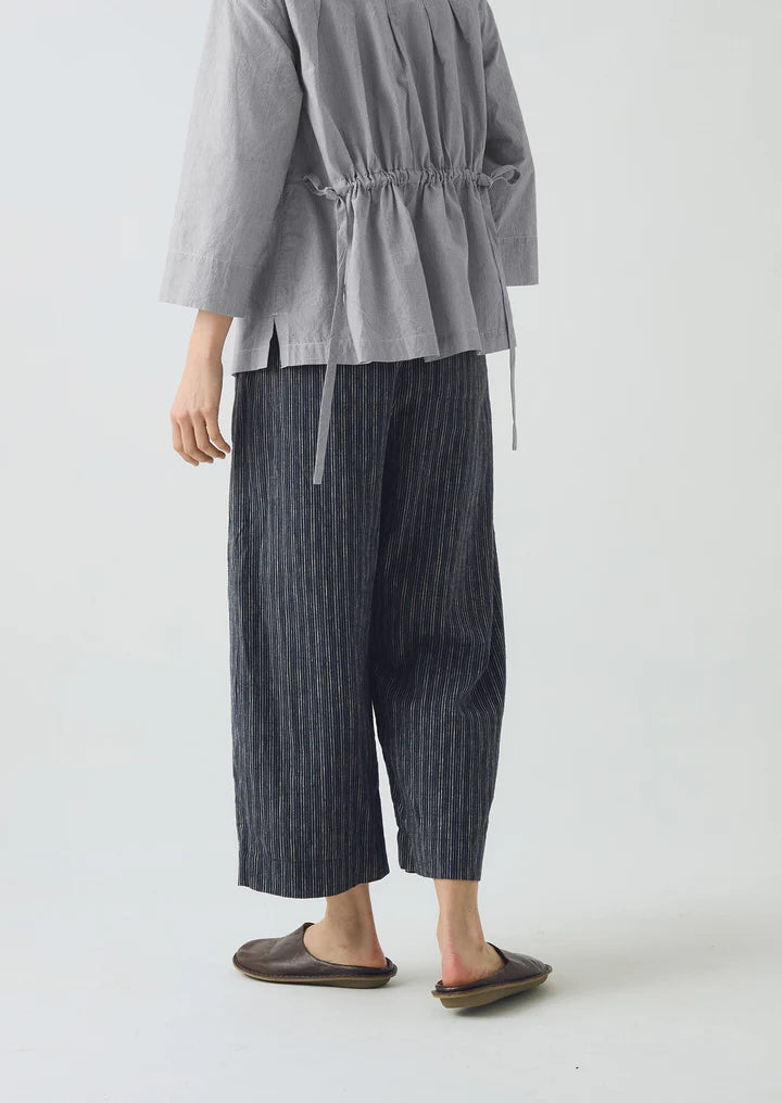 Person wearing a gray jacket and striped pants on a white background