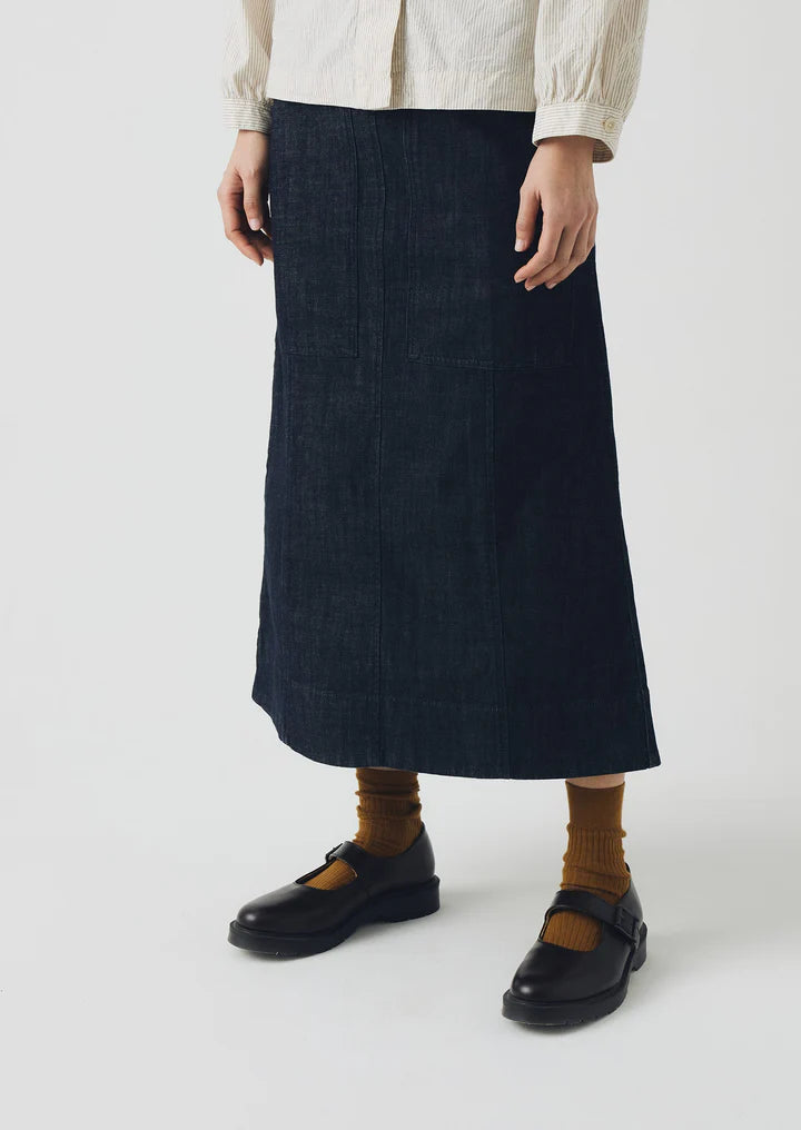 Person wearing a dark denim skirt with a plain background