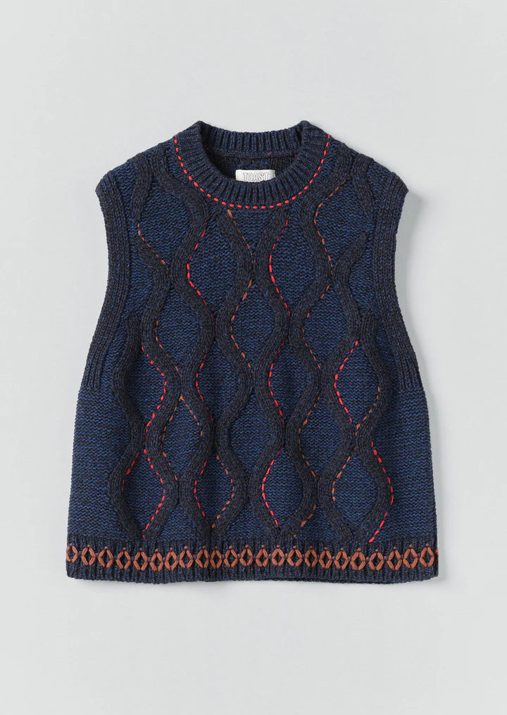 Blue knitted vest with red and orange patterns on a light gray background