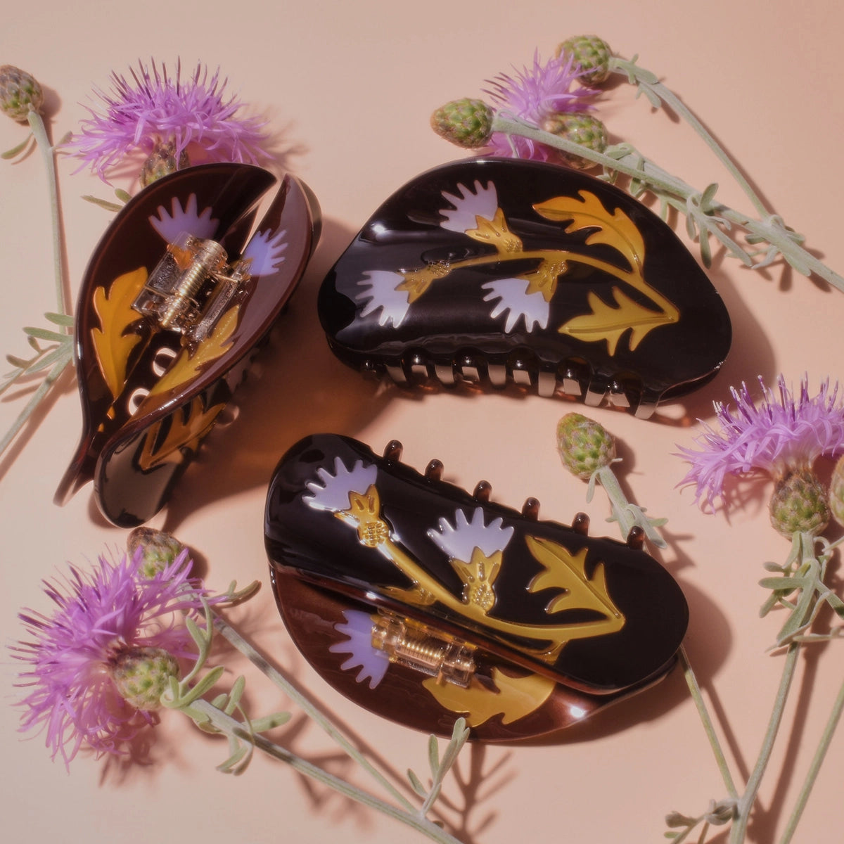 Three floral-patterned hair clips on a beige background with purple flowers.