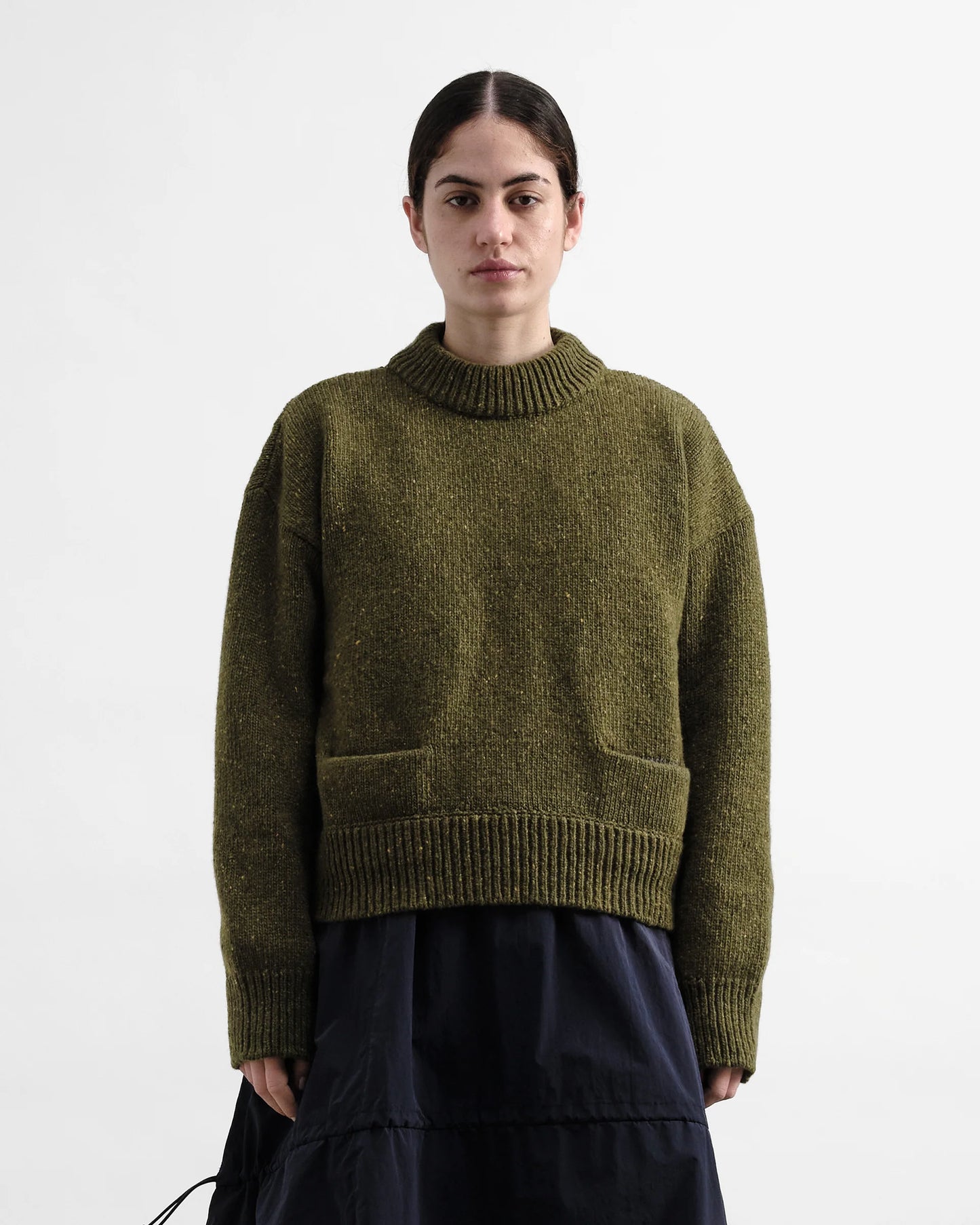 Person wearing a green knitted sweater on a white background