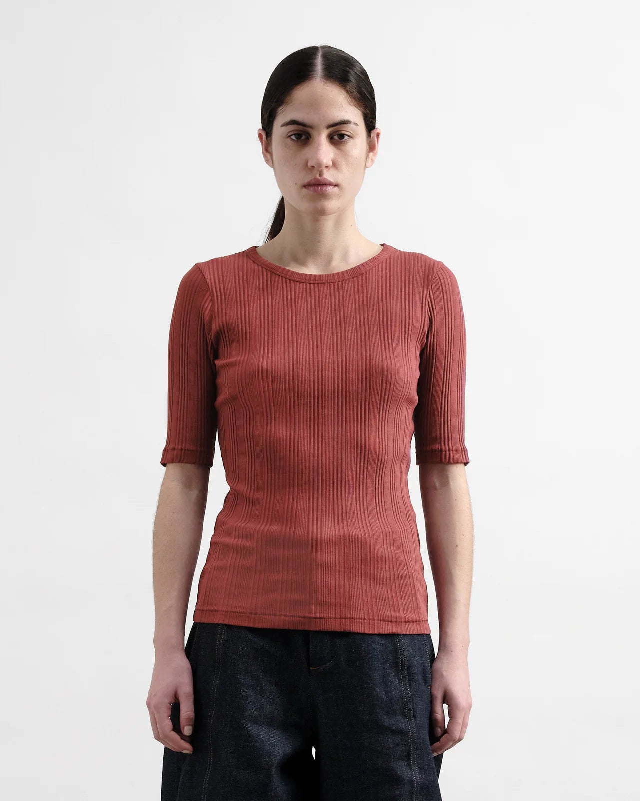 Woman wearing a Burgundy ribbed top against a white background