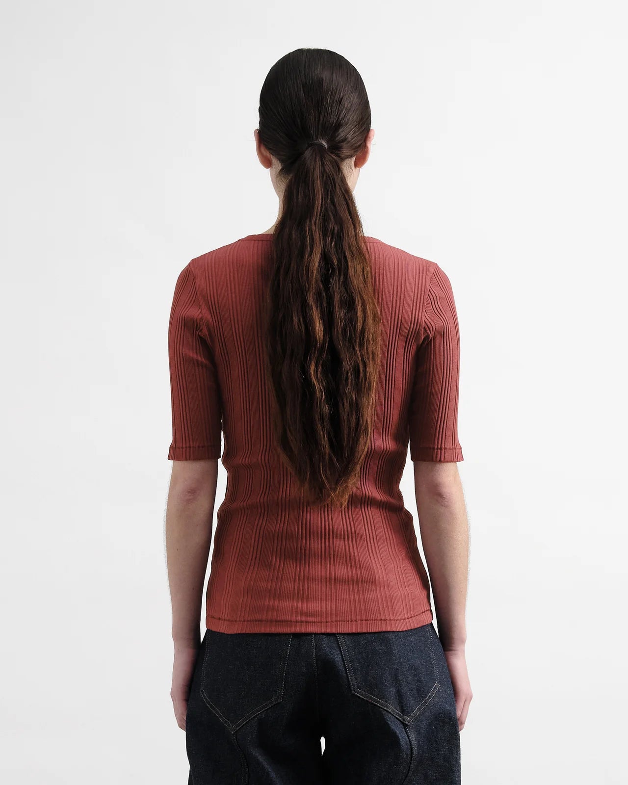 Person wearing a Burgundy ribbed knit top on a white background