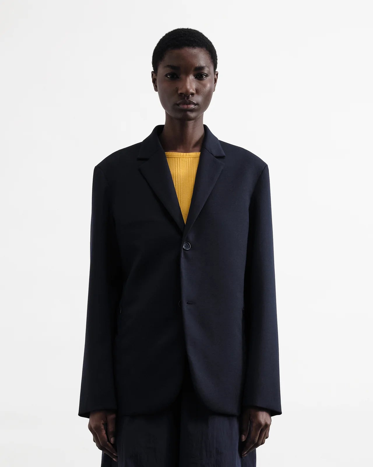 Person wearing a navy jacket over a yellow shirt on a white background