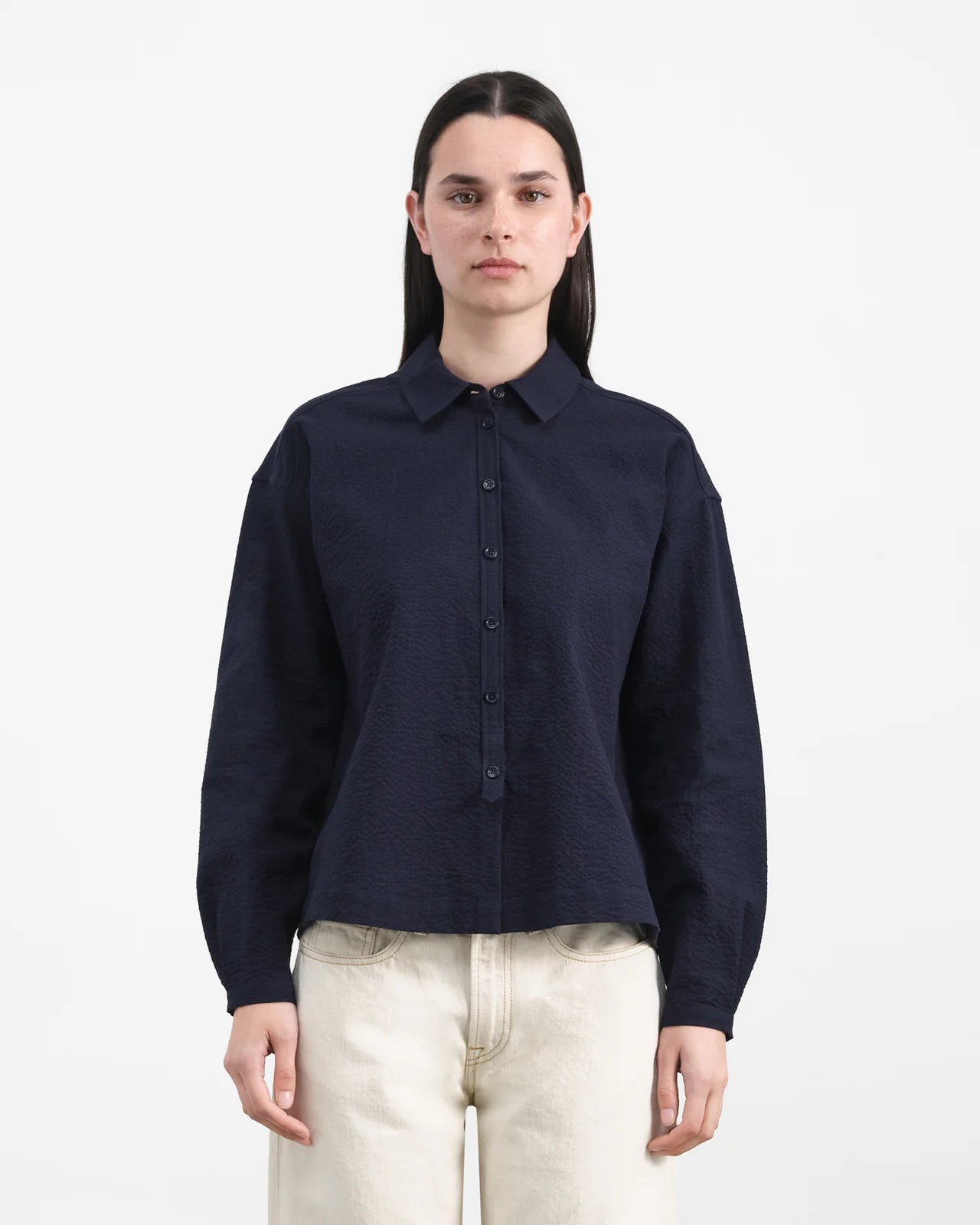 Person wearing a navy blue shirt and light-colored pants on a white background