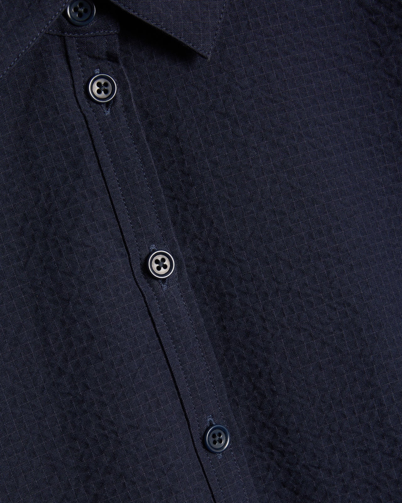 Close-up of a navy blue textured shirt with buttons