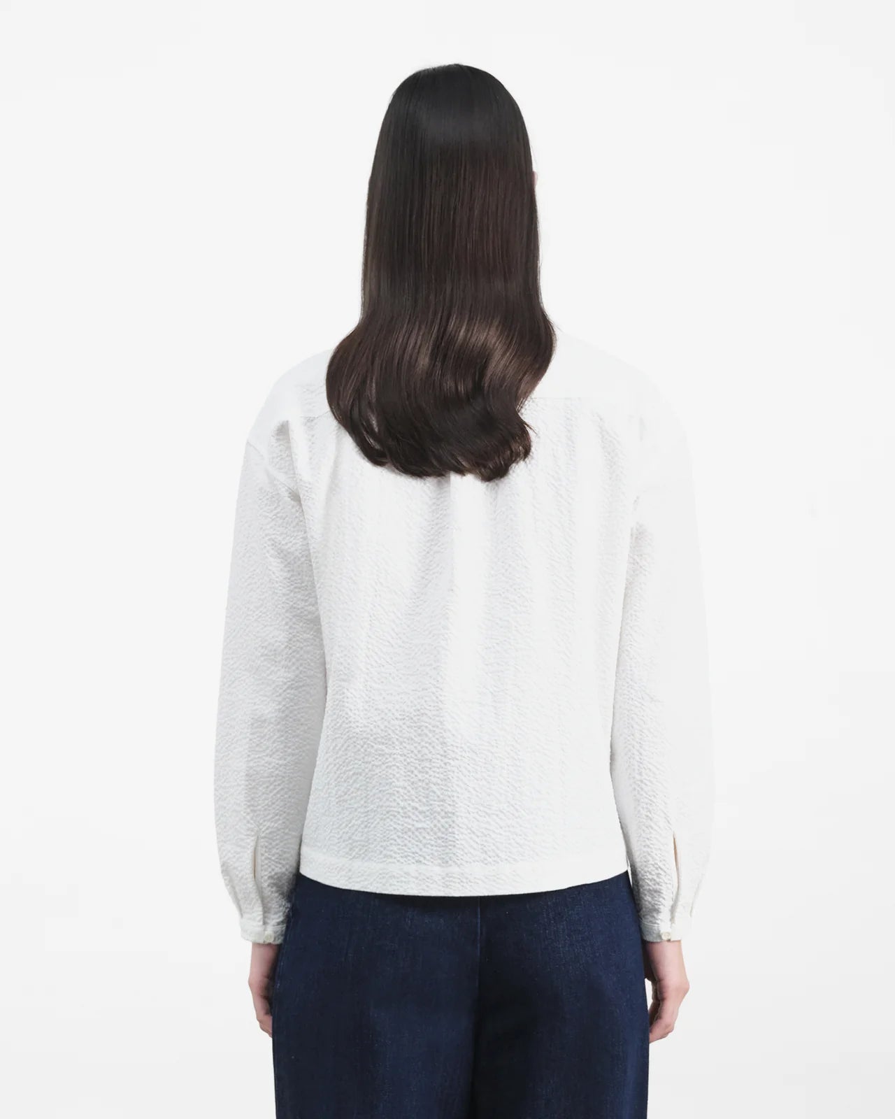 Person wearing a light gray sweater and dark blue pants on a white background