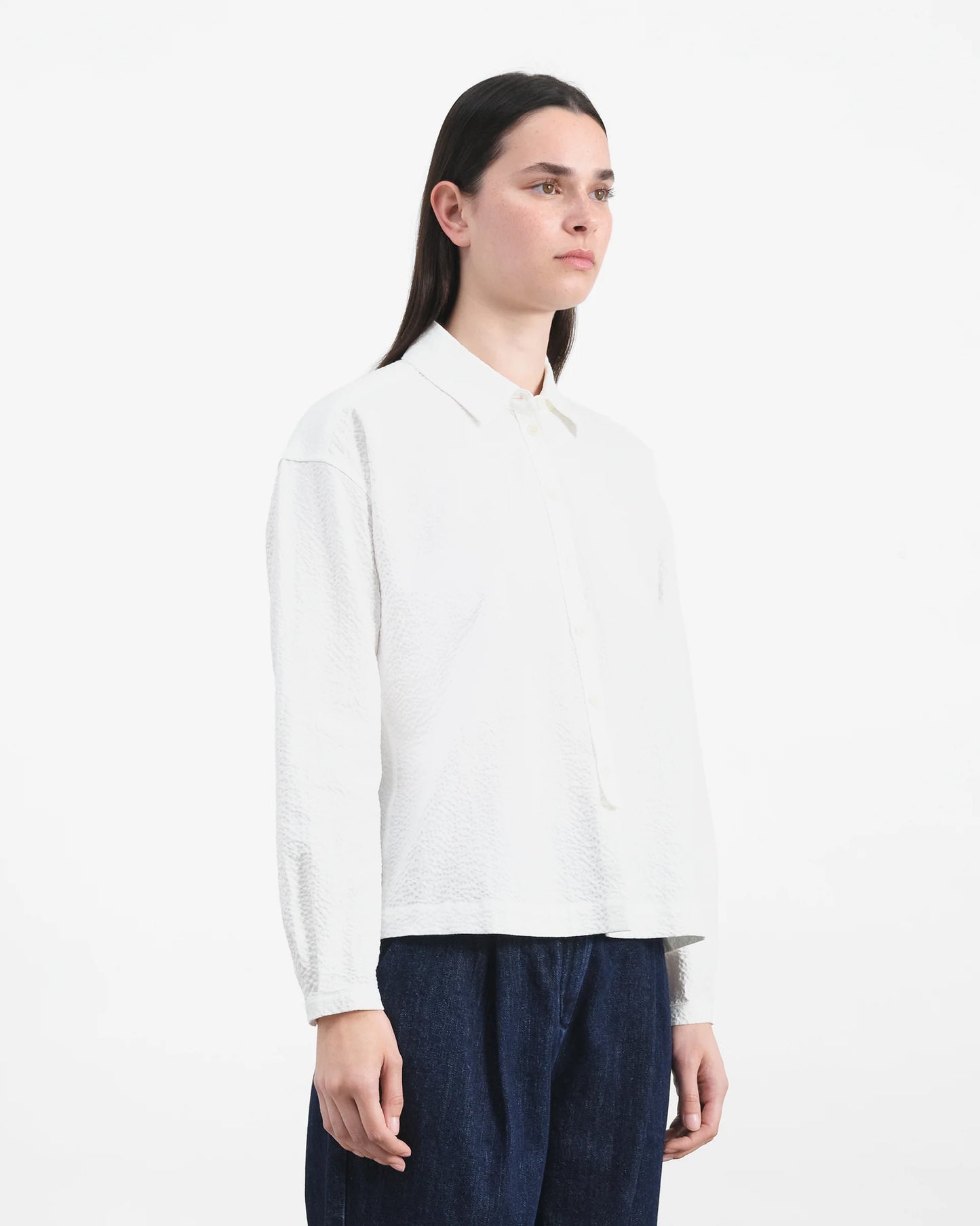 Person wearing a white shirt and dark pants on a white background