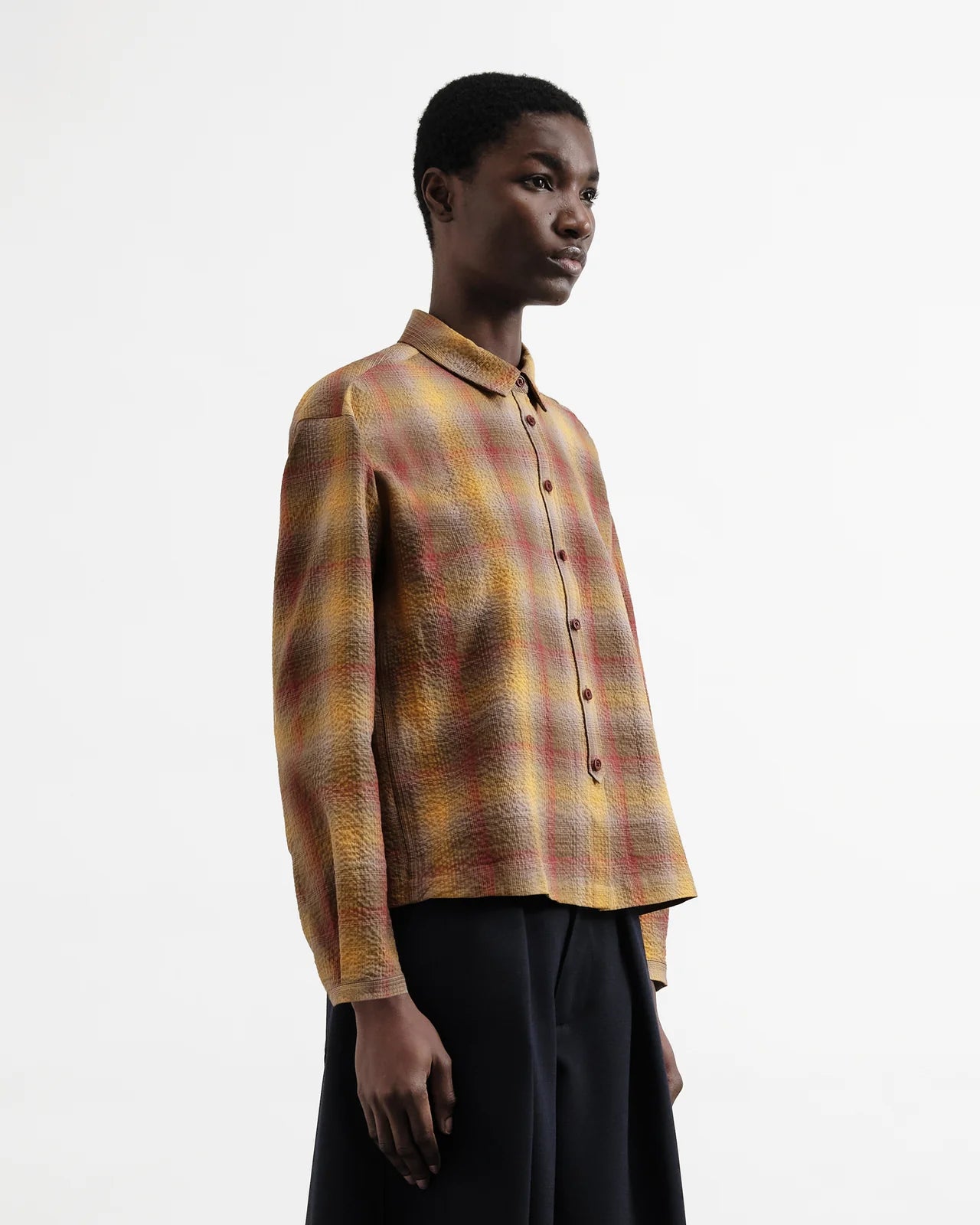 Person wearing a plaid shirt with a plain background