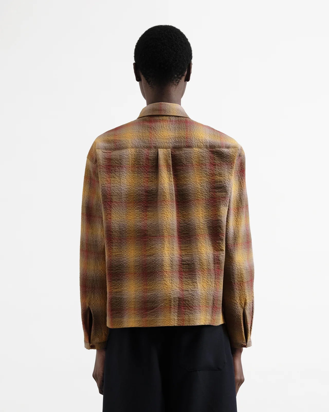 Person wearing a plaid shirt with a neutral background